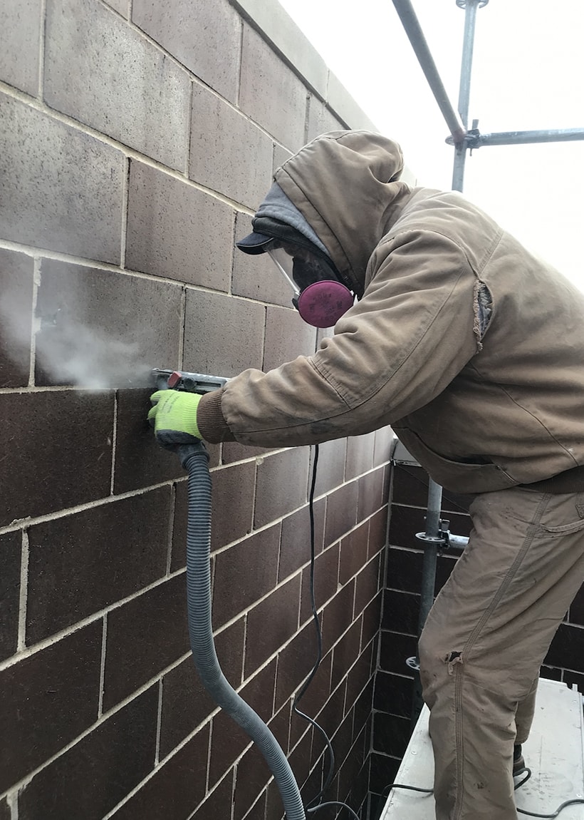 AAA-1 licensed mason Bronek grinding a cinder block wall