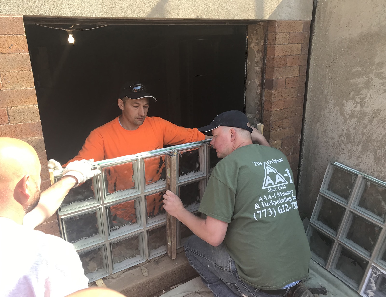 AAA-1 licensed masons installing a wavy-styled glass block window unit in a basement opening