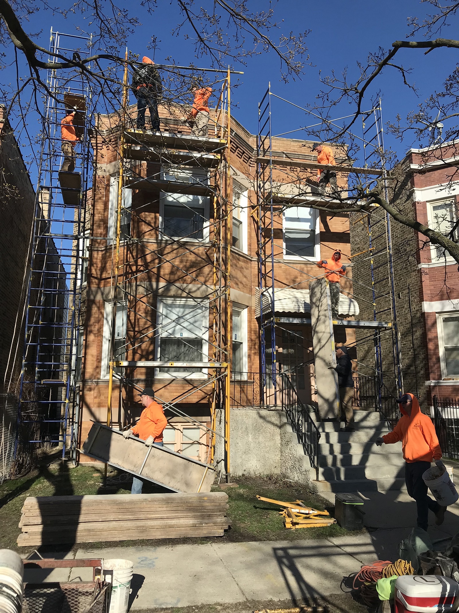 Masons using tubular-pipe scaffolding to access the parapet wall