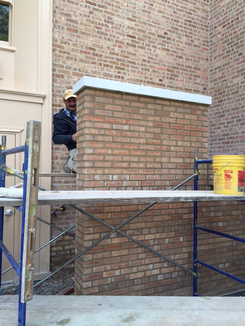 A mason making finishing touches on new brick wall.