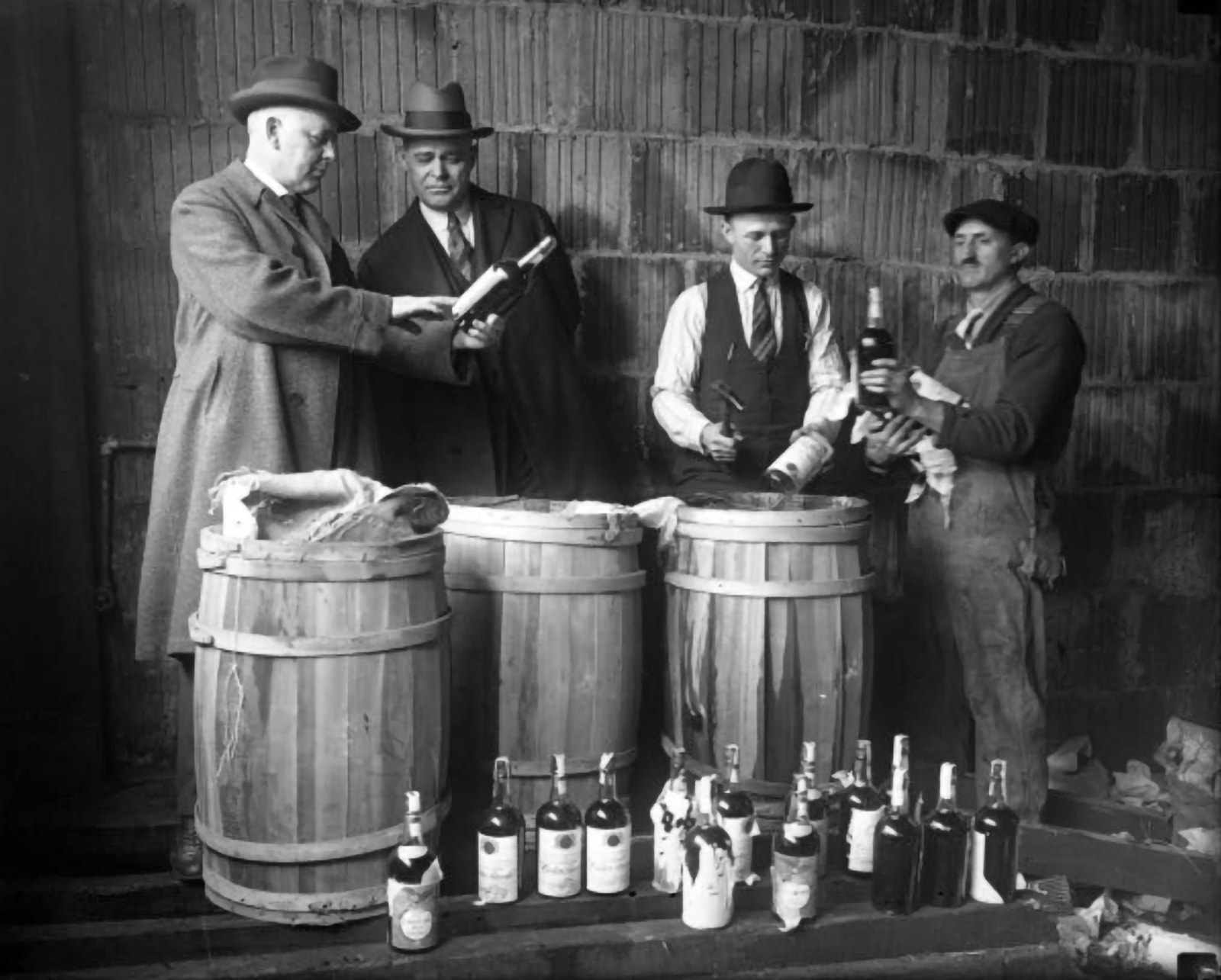 A Prohibition liquor bust in front of a telephone block masonry wall