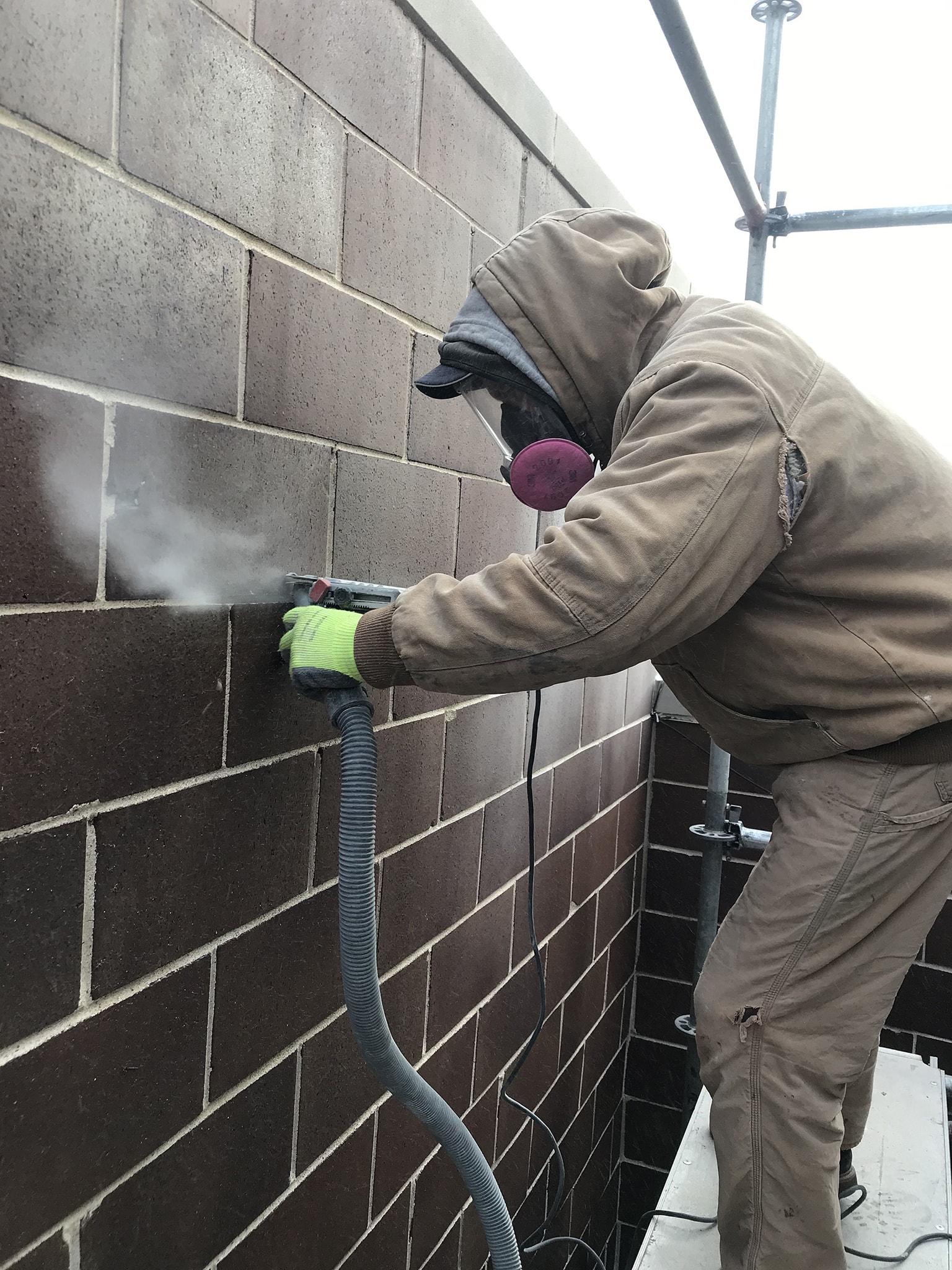 A licensed mason grinding a mortar joint