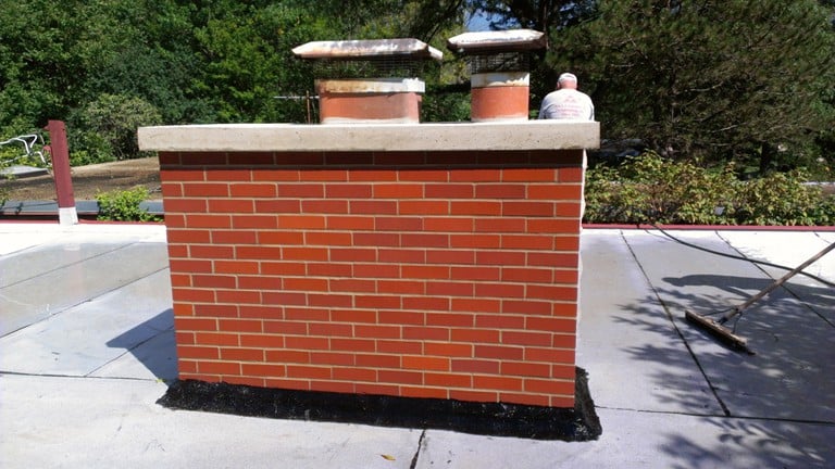 Our correctly built chimney, with Belden bricks, type N mortar, and re-used rain caps, cleaned up and ready for the roofer to return to re-flash the base.
