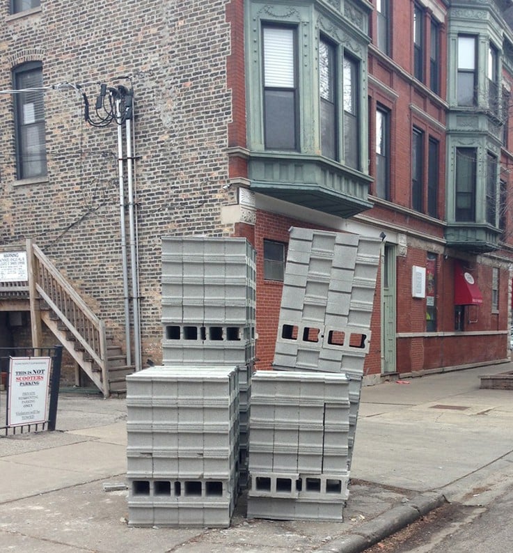 Dangerous, tippy tower of concrete blocks on a sidewalk.