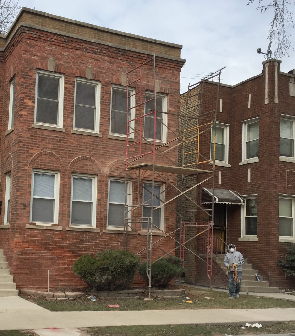 A mason stepping off scaffolding, just having completed spot grinding work