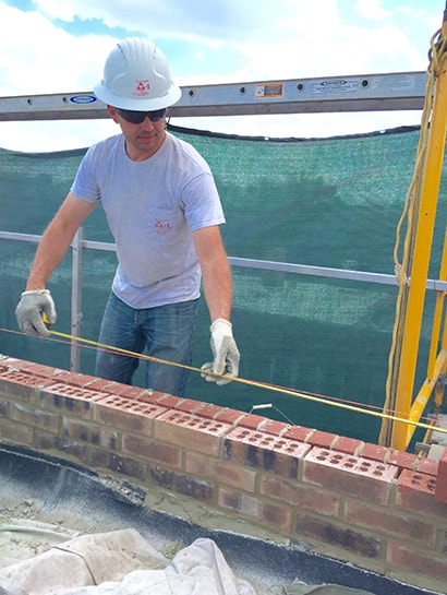 An AAA-1 licensed mason working on a scaffold